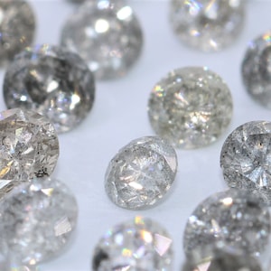 Könnte beinhalten: Eine Sammlung runder, grauer Diamanten mit verschiedenen Einschlüssen. Die Diamanten sind facettiert und haben ein funkelndes, irisierendes Aussehen.