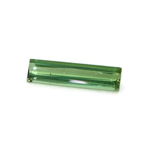Può includere: Una pietra preziosa verde di forma rettangolare e taglio sfaccettato.