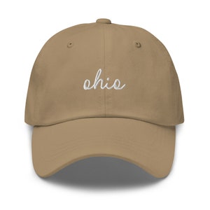 May include: A tan baseball cap with the embroidered word "Ohio" in white script across the front. The cap has a curved brim and a fabric strap closure.