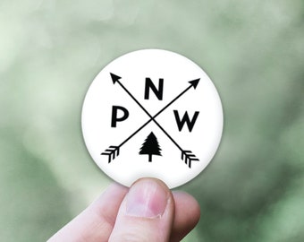 May include: White round sticker with black arrows pointing north, west, and south. The letters "N", "W", and "P" are printed on the sticker. A small pine tree icon is in the center of the sticker.