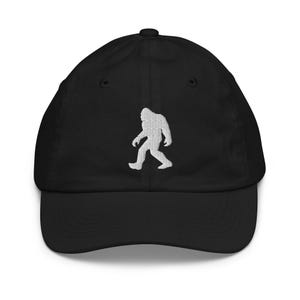 May include: A black baseball cap with a white embroidered silhouette of Bigfoot walking.
