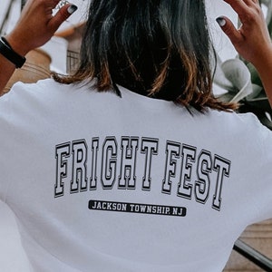 May include: White t-shirt with black text that reads "FRIGHT FEST" in a varsity style font. Below the text is "JACKSON TOWNSHIP, NJ".