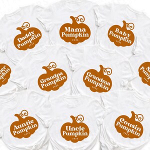 May include: Ten white t-shirts with orange pumpkin designs and text that reads "Brother Pumpkin", "Daddy Pumpkin", "Mama Pumpkin", "Baby Pumpkin", "Sister Pumpkin", "Grandpa Pumpkin", "Grandma Pumpkin", "Auntie Pumpkin", "Uncle Pumpkin", and "Cousin Pumpkin".