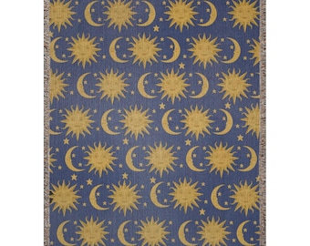 May include: A woven throw blanket with a repeating pattern of suns and moons on a blue background. The suns and moons are a golden yellow color.