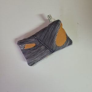 May include: A black and white striped fabric pouch with a mustard yellow geometric design. The pouch has a small white tag that says "Fast Founder".
