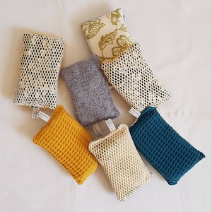 May include: Assortment of seven different textured kitchen scrubbers. The scrubbers are in various colors, including yellow, blue, gray, and white. Some scrubbers have a mesh pattern, while others have a waffle pattern.