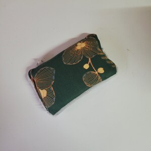 May include: A green fabric pouch with a white lining and a floral pattern in shades of orange and yellow.