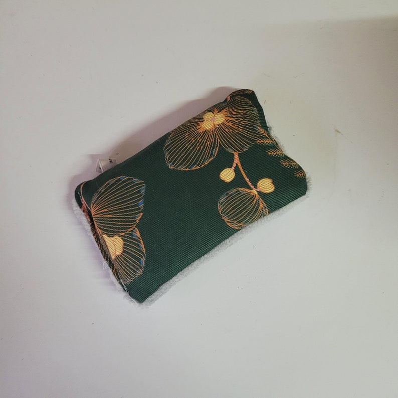May include: A green fabric pouch with a white lining and a floral pattern in shades of orange and yellow.