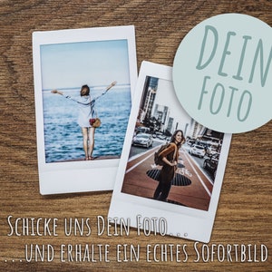 Puede incluir: Dos fotos instant&aacute;neas Polaroid sobre una superficie de madera. La foto superior muestra a una persona con los brazos extendidos de pie en un muelle con vistas al oc&eacute;ano. La foto inferior muestra a una persona caminando por una calle de la ciudad. Un c&iacute;rculo azul claro con el texto "DEIN FOTO" est&aacute; encima de las fotos.