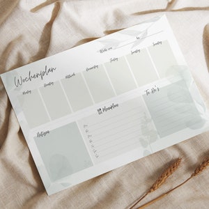 Könnte beinhalten: Ein weißer Wochenplaner mit einem hellgrünen Blumenmuster. Der Planer hat Abschnitte für jeden Tag der Woche, einen Essensplan und eine To-Do-Liste.
