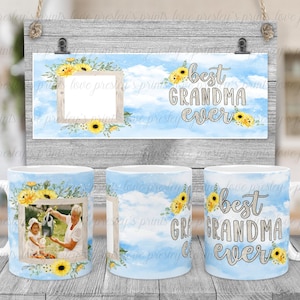 Puede incluir: Dos tazas blancas con nubes de acuarela azul y blanca y girasoles amarillos. Las tazas tienen un marco de fotos con una imagen de una abuela y una nieta. Las tazas tienen el texto "la mejor abuela del mundo" en ellas. Un letrero con el mismo dise&ntilde;o y texto est&aacute; en el fondo.