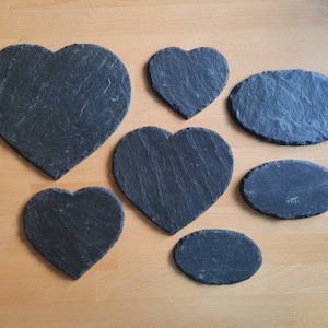 May include: A set of six black slate coasters in various heart and oval shapes.