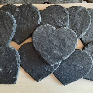 May include: A set of 10 black heart-shaped slate coasters. The coasters are made of natural slate and have a rustic, handmade look.