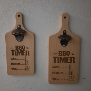 May include: Two wooden BBQ timers with bottle openers. Each timer has the text "-BBQ- TIMER" and cooking levels: Rare, Medium, and Well. The timers are made of light-colored wood and have a metal bottle opener attached.