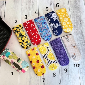 May include: Ten colorful oven mitts with different patterns, including lemons, ladybugs, cacti, and floral designs. The mitts are numbered 1 through 10.