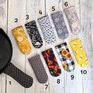 May include: Ten different pot holders with various patterns. The pot holders are made of fabric and have a variety of designs, including floral, geometric, and animal prints. The pot holders are numbered 1 through 10.