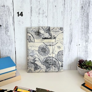 May include: A rectangular fabric sleeve featuring a vintage-style world map print in black and cream. The design includes detailed compass roses, global grid lines, and the text "THE WORLD" printed on the front. It has a small top flap closure.