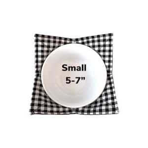 May include: Black and white checkered bowl cozy with a white bowl inside. The bowl cozy is labeled "Small 5-7" inches.