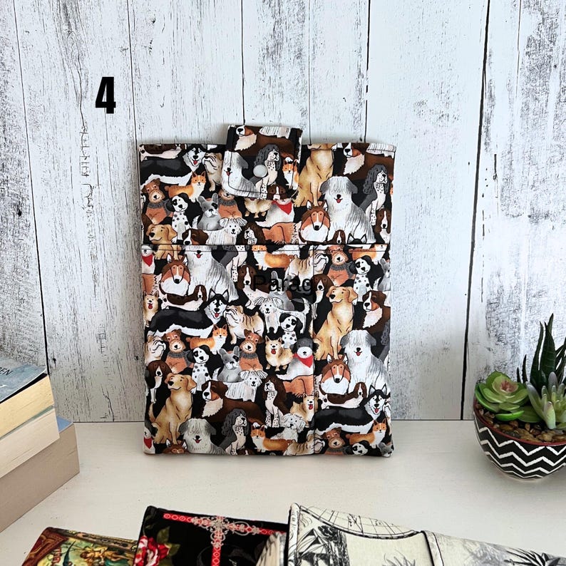 May include: A rectangular fabric pouch featuring a repeating pattern of various dog breeds in shades of brown, black, white, and tan. The pouch has a top flap with a snap closure and a small pocket on the front. The number 4 is visible in the corner.