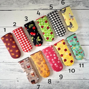 May include: Eleven colorful oven mitts with different patterns, including checkered, floral, and cartoon designs. The mitts are numbered 1 through 11.