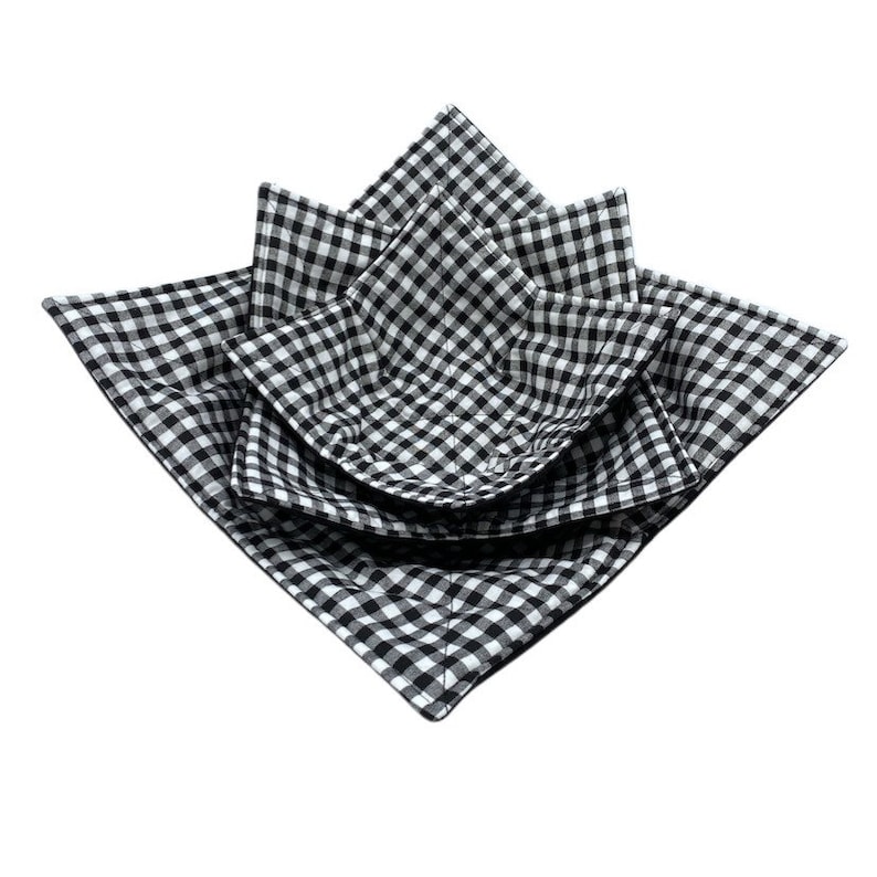 May include: Three black and white gingham fabric bowls, nested together. The bowls are made of quilted fabric and are designed to hold items like fruit or snacks.