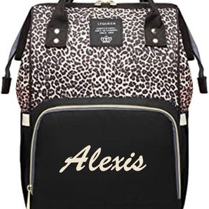 Pu&ograve; includere: Una borsa per pannolini nera e marrone con stampa leopardata e una tasca nera con cerniera sul davanti. La tasca &egrave; ricamata con il nome "Alexis" in color crema.