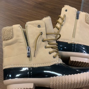 Op de afbeelding: Beige su&egrave;de winterlaarzen met zwarte rubberen zolen en bruine veters. De laarzen hebben een rits aan de zijkant en een voering van imitatiebont.