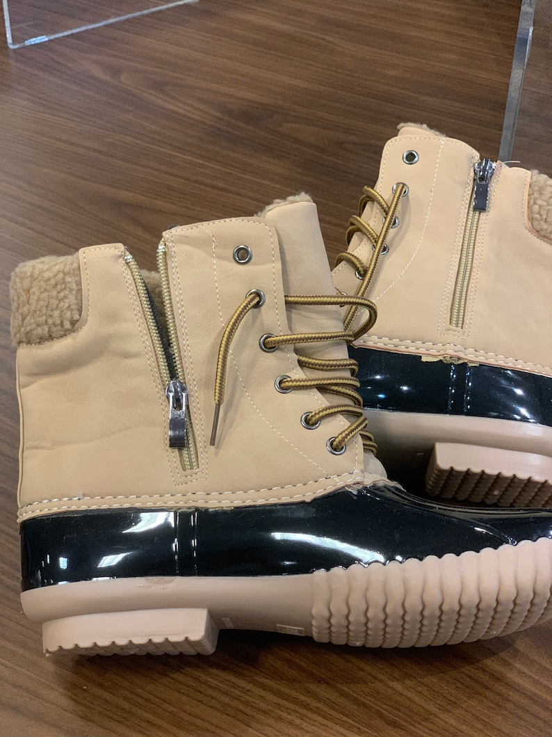 Op de afbeelding: Beige su&egrave;de winterlaarzen met zwarte rubberen zolen en bruine veters. De laarzen hebben een rits aan de zijkant en een voering van imitatiebont.
