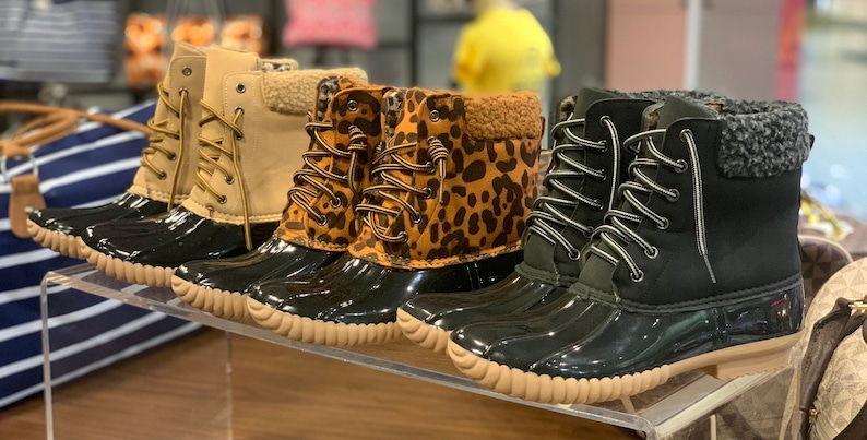 Op de afbeelding: Vier paar dames winterschoenen met verschillende patronen. De laarzen zijn zwart met een bruine rubberen zool en hebben veters. Een paar is beige, een paar is luipaardprint en twee paar zijn zwart met een grijze bontkraag.