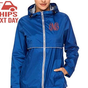 May include: A royal blue hooded jacket with a silver zip and a white trim. The jacket has a monogrammed initial on the left chest.