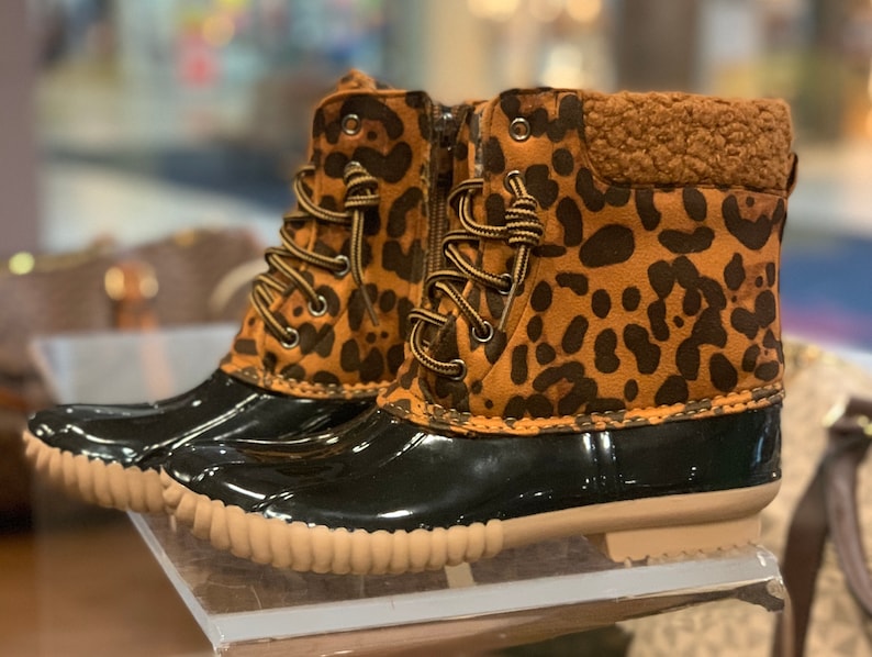 Op de afbeelding: Bruine en zwarte enkellaarsjes met luipaardprint, zwarte rubberen zolen en een bruine voering van imitatiebont.