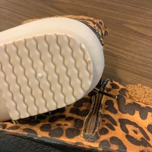 Op de afbeelding: Bruine en zwarte enkellaarsjes met luipaardprint, een rits aan de zijkant en een witte rubberen zool.