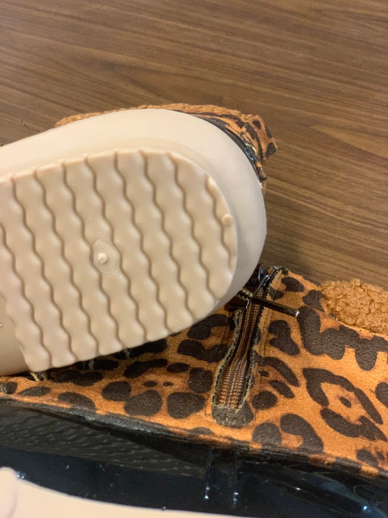 Op de afbeelding: Bruine en zwarte enkellaarsjes met luipaardprint, een rits aan de zijkant en een witte rubberen zool.