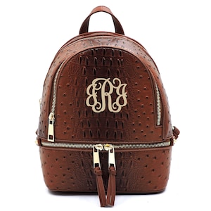 May include: A brown faux leather backpack with a gold zipper and a gold monogram "ERJ" on the front.
