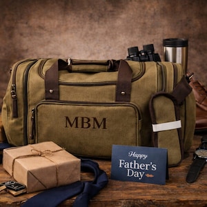 May include: A Father's Day gift set featuring a green canvas duffel bag with brown leather accents and the initials "MBM". Includes a watch, shoes, tie, gift box, binoculars, and a "Happy Father's Day" card.