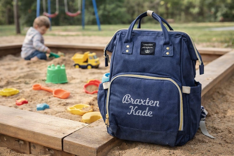 Navy diaper bag with baby names embroidered on front pocket.