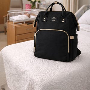 Black diaper bag on baby bed.