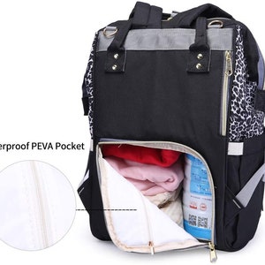 Pu&ograve; includere: Borsa per pannolini nera e grigia con un accento a stampa leopardata. La borsa ha una grande tasca con cerniera sul davanti con una fodera impermeabile. La borsa &egrave; aperta e mostra una coperta rossa e rosa all'interno.