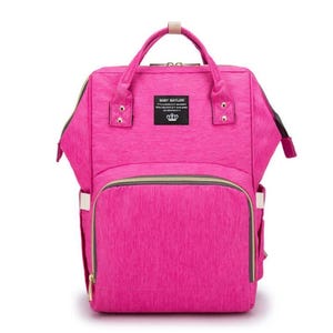A pink diaper bag backpack with gold accents and a zippered pocket on the front.