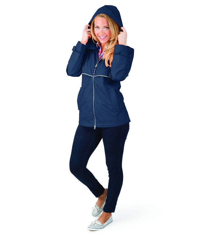 May include: A navy blue hooded jacket with a zipper closure and reflective piping. The jacket is worn by a person with blonde hair and is standing on a white background.