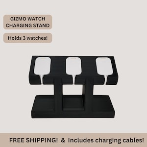 May include: Black wooden Gizmo watch charging stand with three white charging pads. The stand is designed to hold three watches. Text on the image reads "GIZMO WATCH CHARGING STAND" and "Holds 3 watches!"