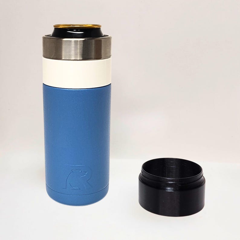 May include: A blue and white insulated beverage holder with a stainless steel rim, holding a can. A separate black base sits beside it. The holder features a bear logo.