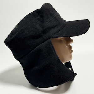 May include: A black fleece cap with ear flaps and a brim. The cap is designed to keep the wearer warm in cold weather.
