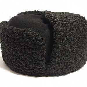 May include: A black fur hat with a fold-down ear flap. The hat is made of a soft, fuzzy material and has a round shape.