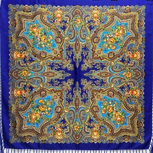 Peut inclure: Un foulard en soie bleu à motifs paisley avec une bordure à franges. Le foulard présente un motif floral avec des accents jaunes, orange et bruns.