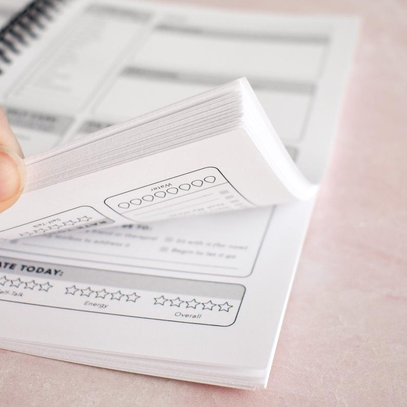a hand holding open a notebook or book with a page that appears to be a survey or feedback form. The form has multiple sections, including a section for rating the form and another section for rating the user's experience. The form also includes a section for rating the user's energy levels.