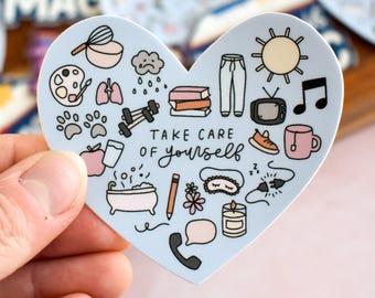 May include: A heart-shaped sticker with a light blue background featuring various small illustrations including a sun, books, a bathtub, a candle, and a telephone. The text "TAKE CARE OF yourself" is printed in the center in black ink.