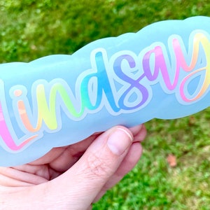 Pastel rainbow name sticker that can be personalized for you. Script/cursive font in pastel rainbow gradient layered onto white outline.