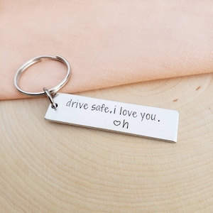 May include: Silver keychain with the text "drive safe. i love you." and a small heart symbol.