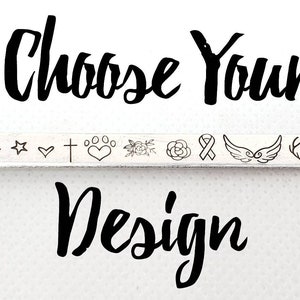 May include: Choose Your Design. A row of 14 different small design options for jewelry, including mountains, a heart, a star, a cross, paw prints, a flower, a rose, a ribbon, wings, antlers, a lotus flower, and elephants.